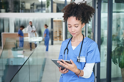 Buy stock photo Cropped shot of an attractive young nurse standing and using a digital tablet in the clinic