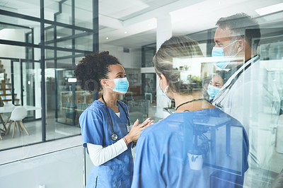 Buy stock photo Cropped shot of a handsome mature doctor standing with his nurses and having a discussion in the clinic