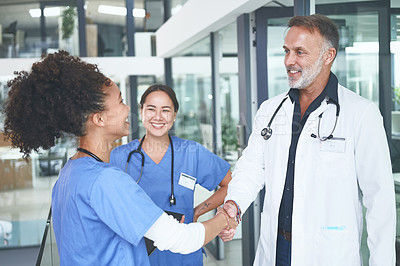 Buy stock photo Cropped shot of a handsome mature doctor standing and shaking a nurse's hand in the clinic
