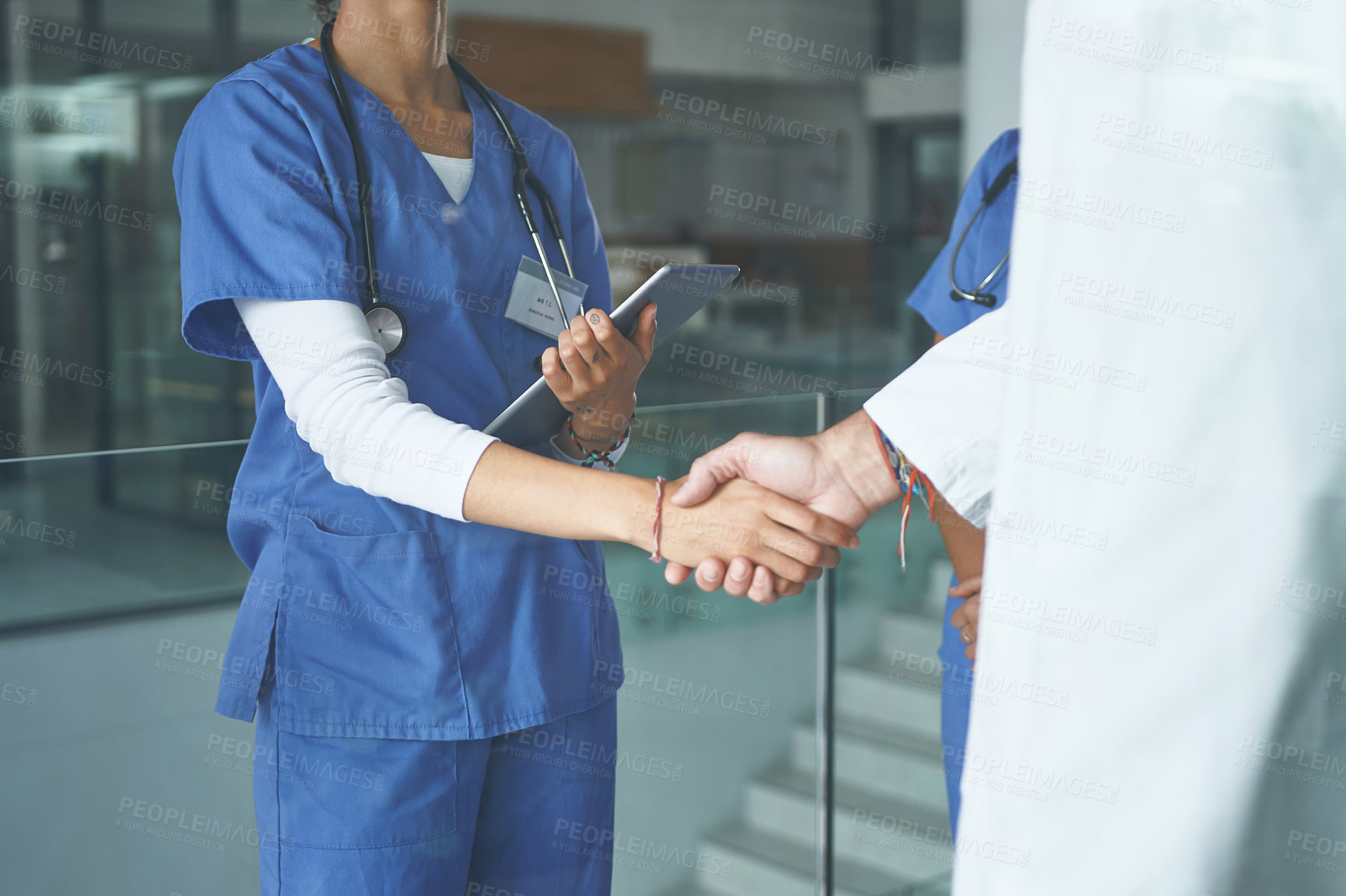 Buy stock photo Cropped shot of an unrecognizable nurse standing and shaking a doctor's hand in the clinic