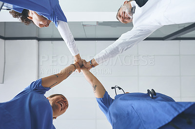 Buy stock photo Low angle shot of a diverse group of healthcare professionals standing and giving each other a high five