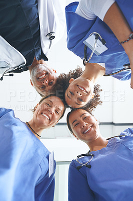 Buy stock photo Low angle portrait of a diverse group of healthcare professionals standing huddled together with their heads together in the middle