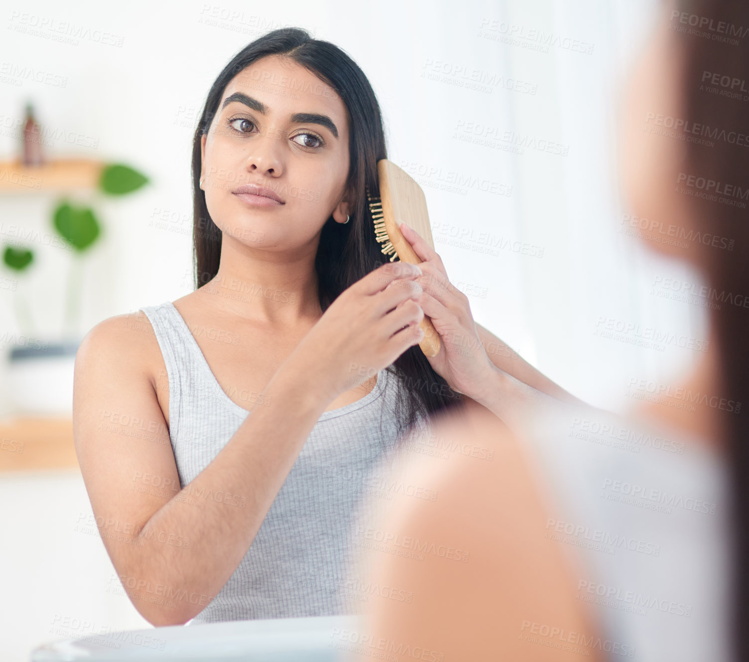 Buy stock photo Shot of young woman brushing her hair in front of the mirror