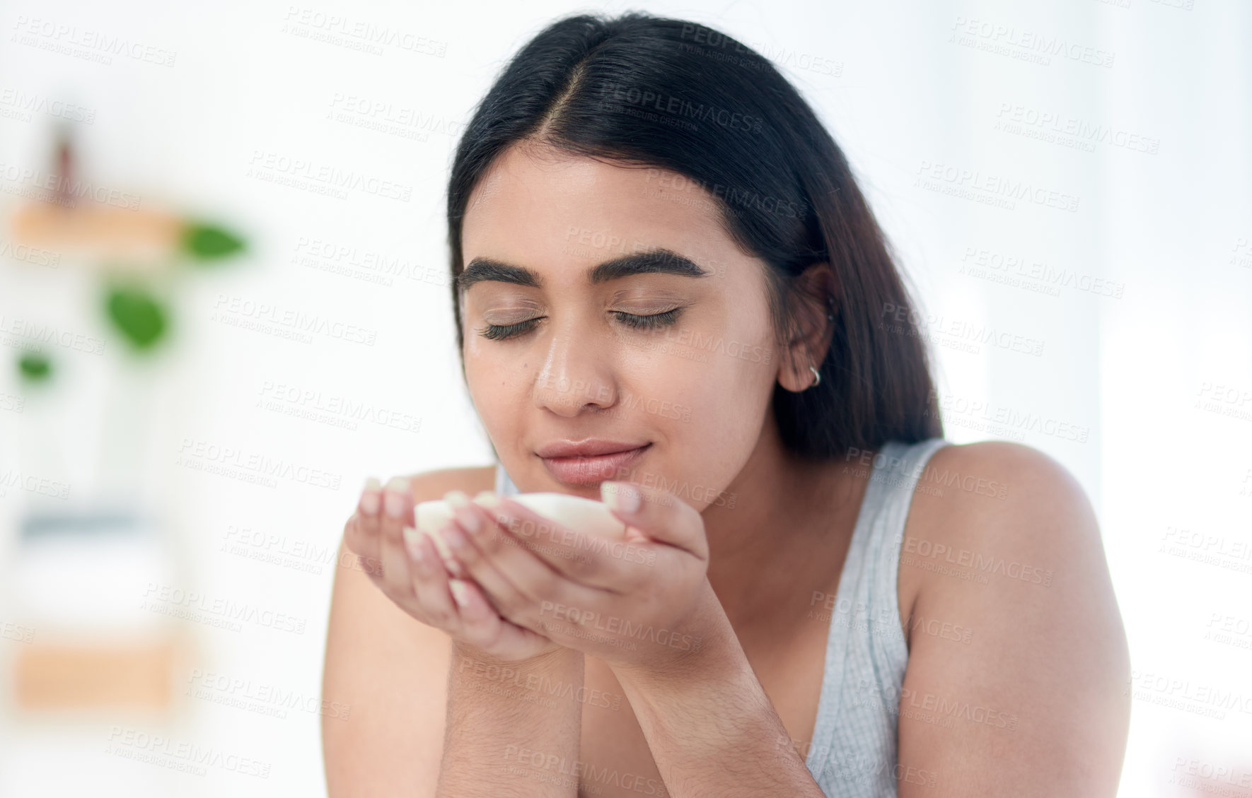 Buy stock photo Shot of young woman smelling some skincare product