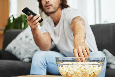 Buy stock photo Shot of man sitting on the couch eating popcorn and watching tv