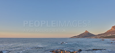 Buy stock photo Beautiful view of a calm ocean and mountains with a blue sky background and copy space. Stunning nature landscape of the sea and horizon close to Lion's Head tourism destination in Cape Town