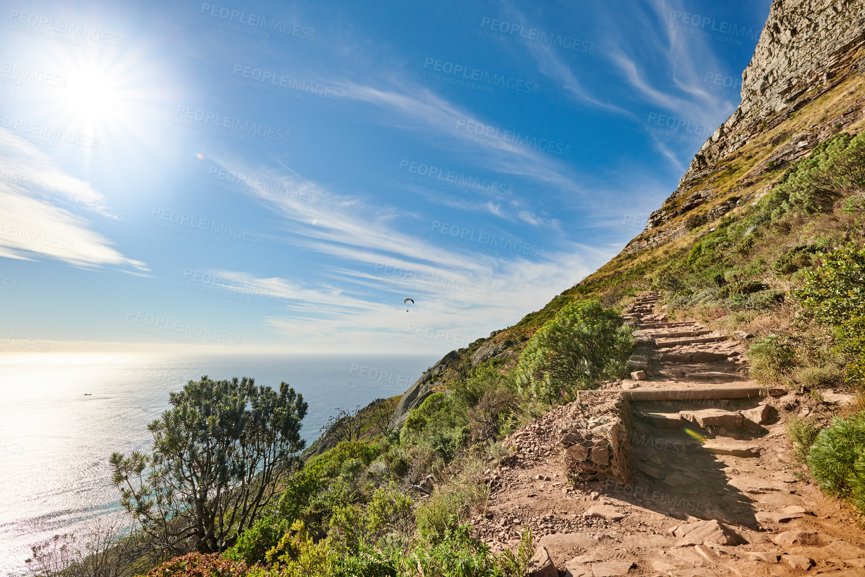 Buy stock photo Copy space with scenic coast and rocky mountain slope with cloudy blue sky background. Rugged landscape of plants growing on a cliff by the sea with hiking trails to explore in Cape Town South Africa