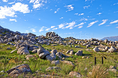 Buy stock photo Secluded hiking location for scenic nature. Landscape of rocky mountain with boulders against a blue sky in summer. Green field with rocks and wild grass growing on sunny day outside with copy space