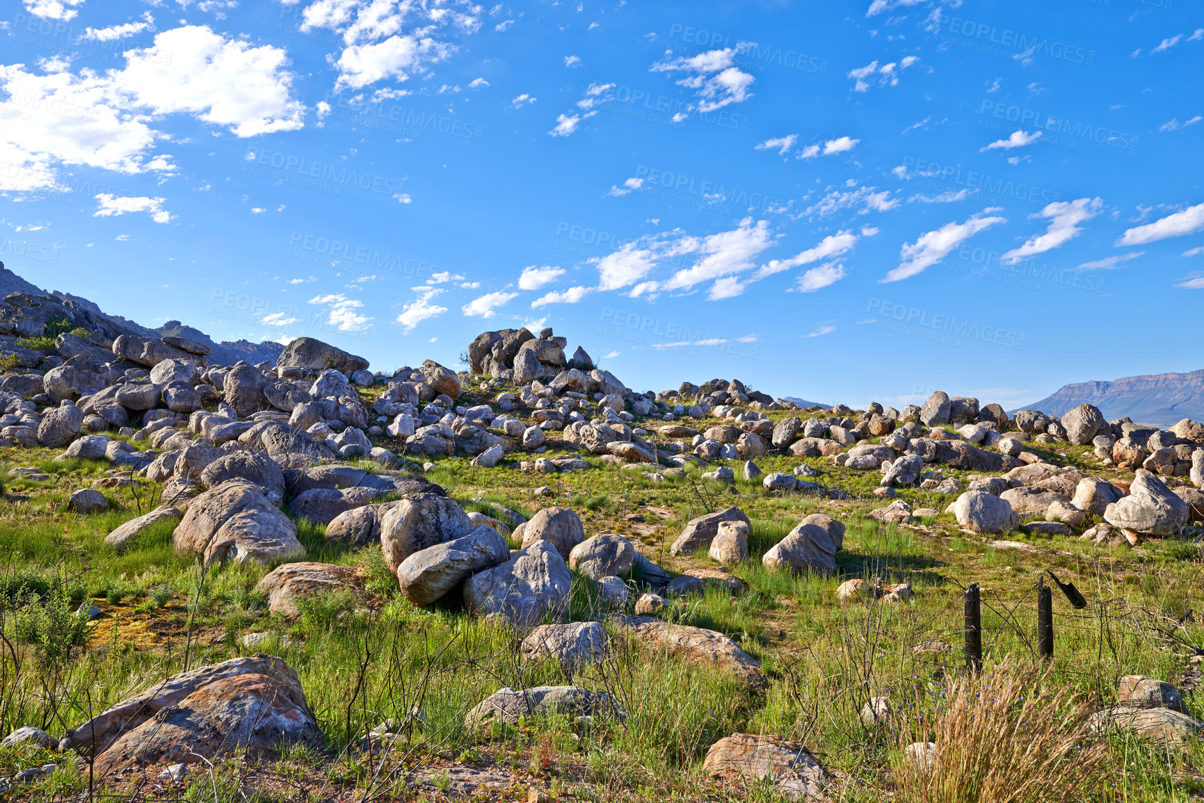 Buy stock photo Secluded hiking location for scenic nature. Landscape of rocky mountain with boulders against a blue sky in summer. Green field with rocks and wild grass growing on sunny day outside with copy space