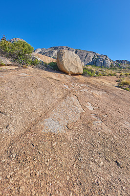 Buy stock photo Mountainside with large boulders and lush plants with copy space. Indigenous dry fynbos and wild grass growing on a rocky hill in summer warm weather. Quiet nature scene with tropical weather 