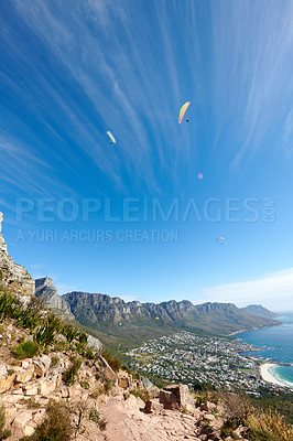 Buy stock photo People paragliding from a mountain with a scenic view in summer. Tourists having fun and doing adventurous activities while on holiday in a clear blue sky. People hand gliding from a cliff in nature