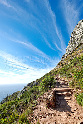 Buy stock photo Scenic mountain hiking trail with copy space, rough rocks or stones leading to beautiful view of ocean or sea from the peak. Landscape of rough path with rocks and blue sky in remote nature reserve