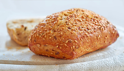 Buy stock photo A fresh home baked loaf of wholegrain or wholewheat, sesame seed bread on a board, ready to be cut. For a healthy diet and lifestyle eat food that's high in fibre. 