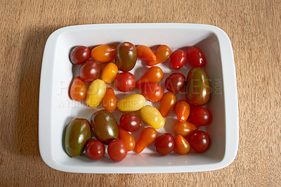 Buy stock photo Closeup of vibrant red roma tomatoes in glass bowl served on wood table for diet, healthy salads or nutrition. Above view of fresh, vitamin fruit organically farmed in home garden or agriculture farm