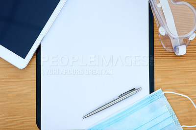 Buy stock photo High angle shot of a digital tablet, clipboard, pen, protective glasses and face mask on a table