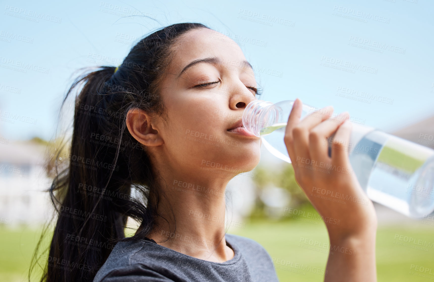 Buy stock photo Shot of a young woman drinking water after her workout at the park