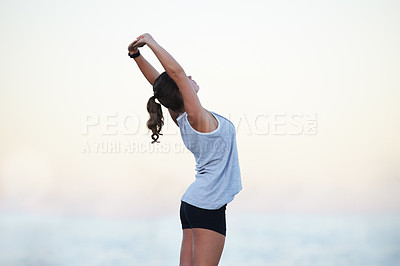 Buy stock photo Shot of a sporty young woman stretching outdoors