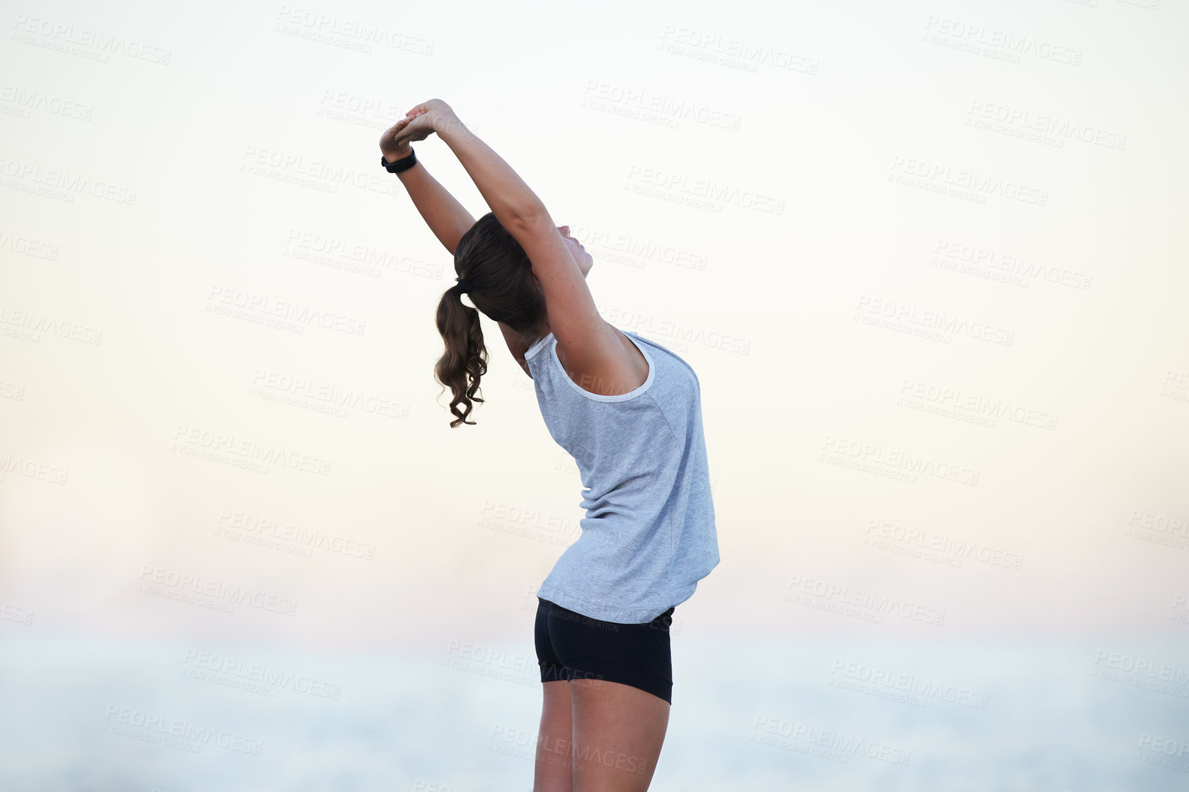 Buy stock photo Shot of a sporty young woman stretching outdoors