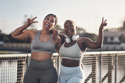 Buy stock photo Shot of two young women showing the peace gesture while out for a workout