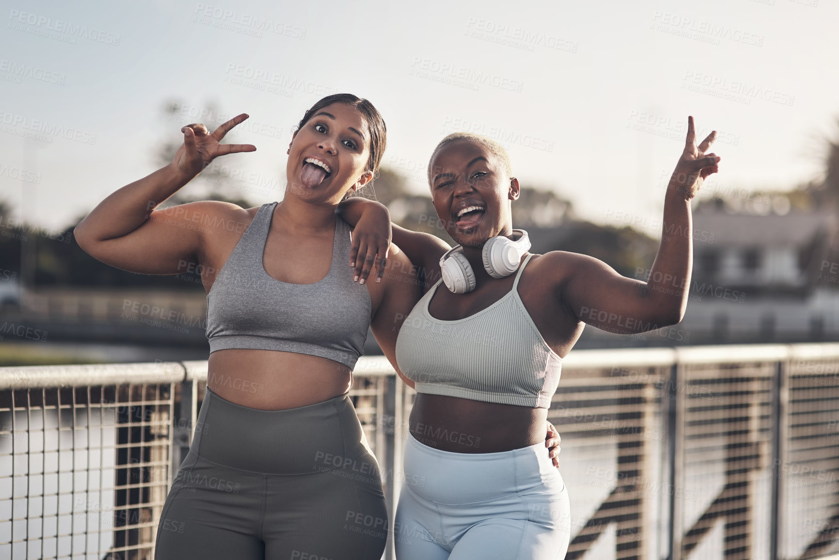 Buy stock photo Shot of two young women showing the peace gesture while out for a workout