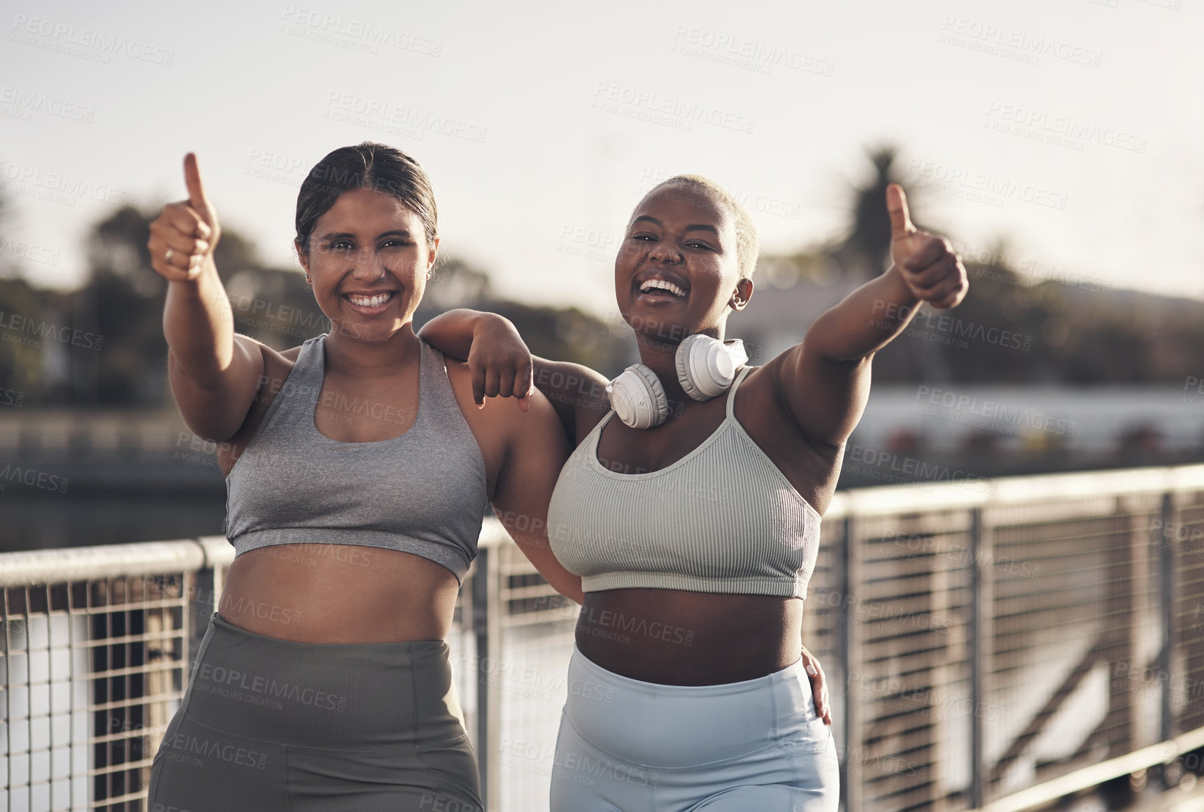 Buy stock photo Shot of two young women showing thumbs up while out for a workout