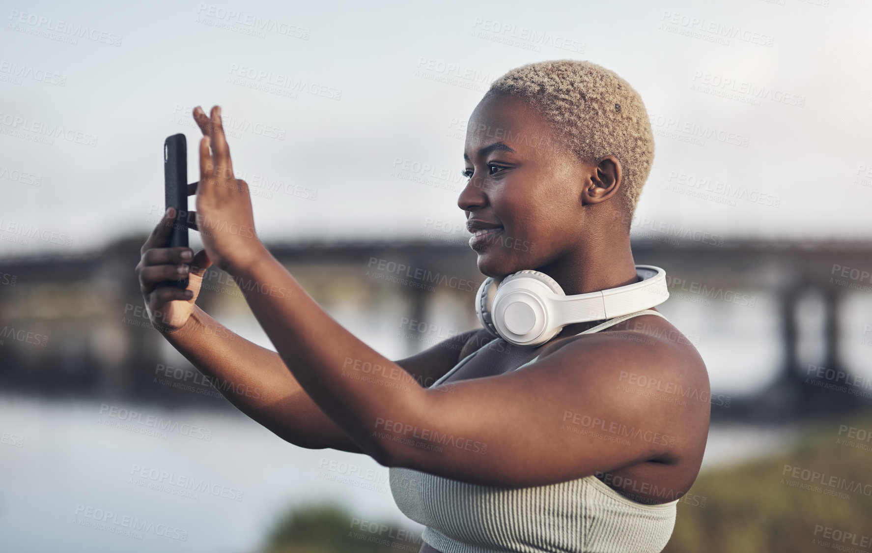 Buy stock photo Shot of a young woman taking pictures on her cellphone while out for a workout