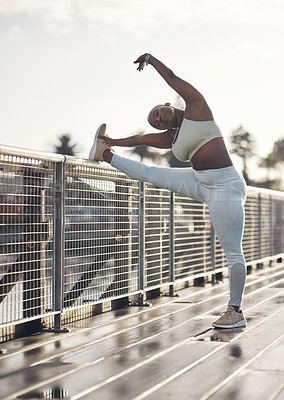 Buy stock photo Shot of a young woman stretching on a footbridge