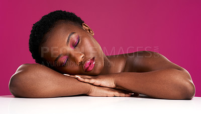 Buy stock photo Studio shot of a beautiful young woman resting on a table with her eyes closed against a pink background