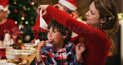 Buy stock photo Shot of a young woman putting her son’s hat on during a Christmas dinner party at home