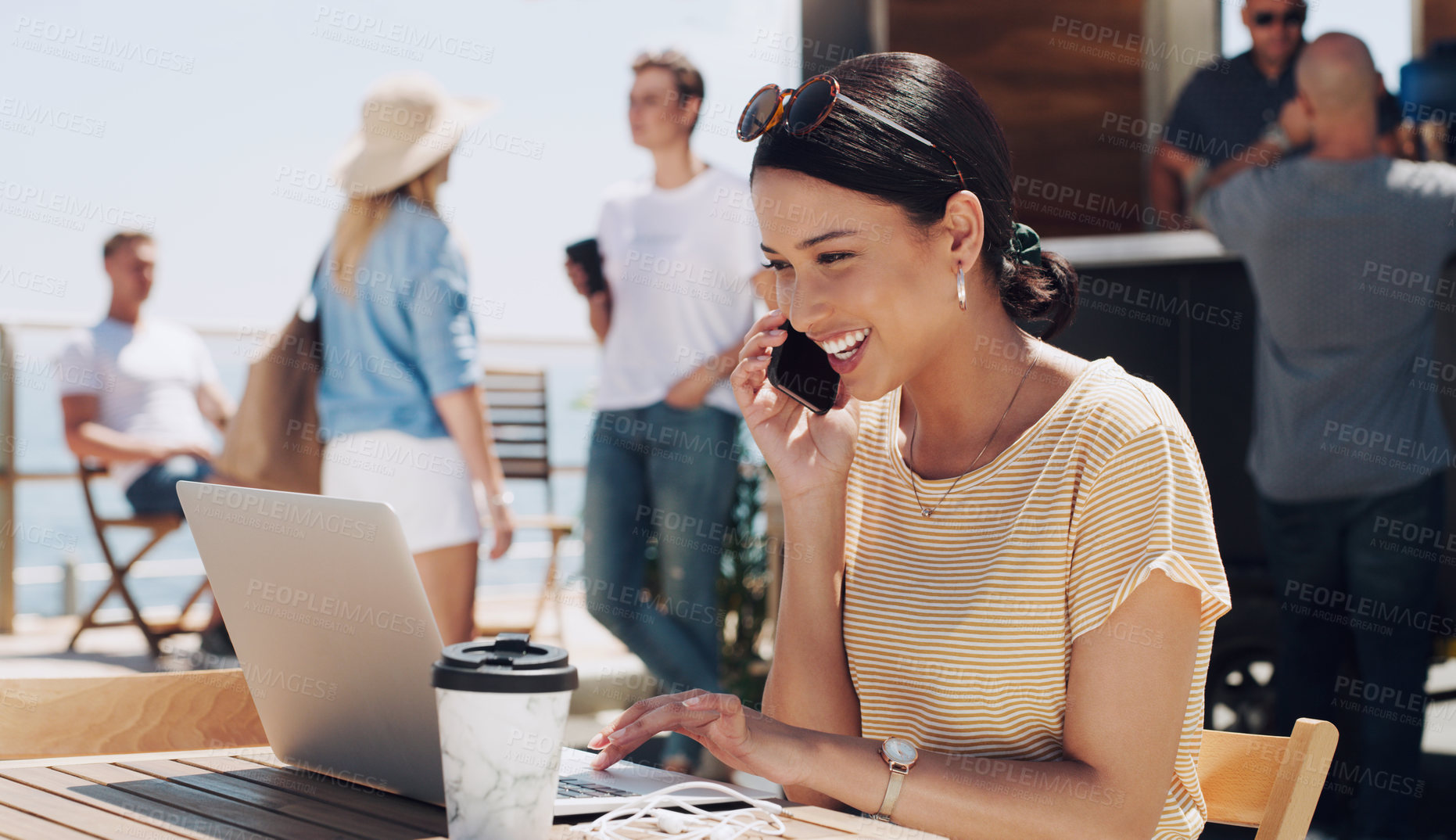 Buy stock photo Shot of a young working on her laptop while on a phone call  sitting outside