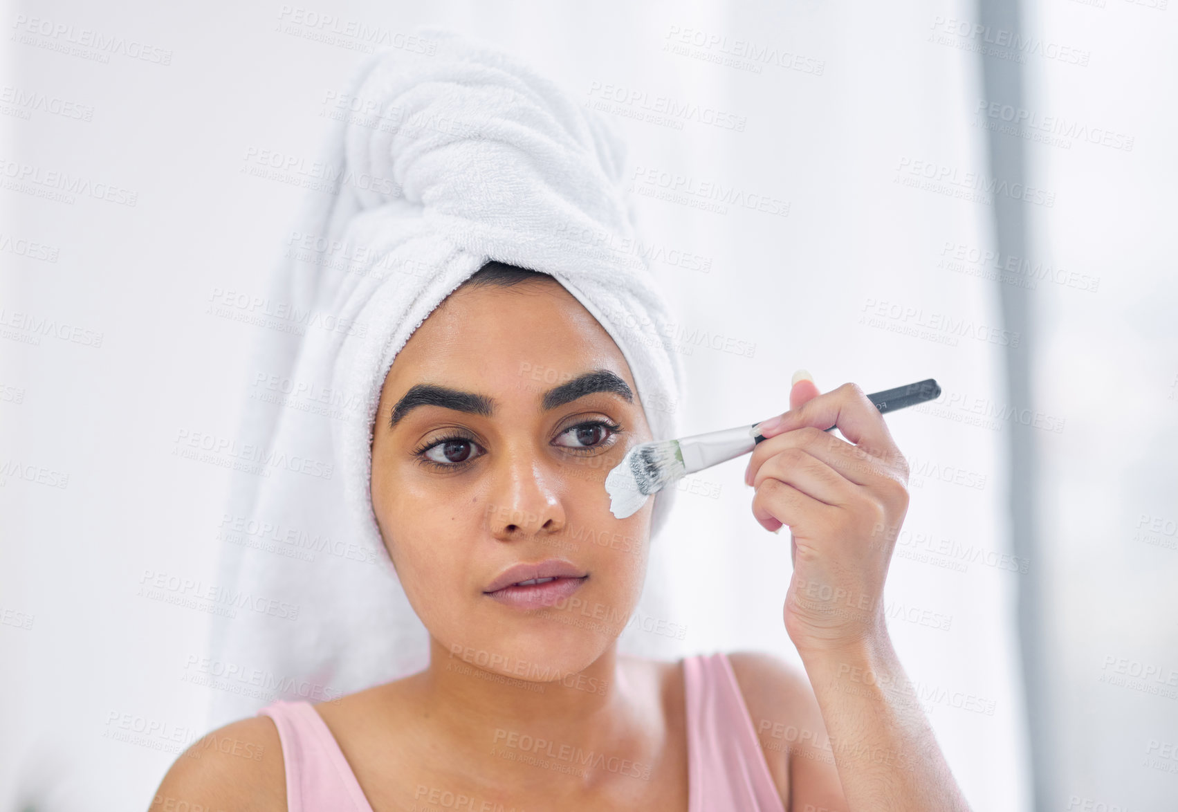 Buy stock photo Shot of a woman using a paintbrush to apply a product to her face