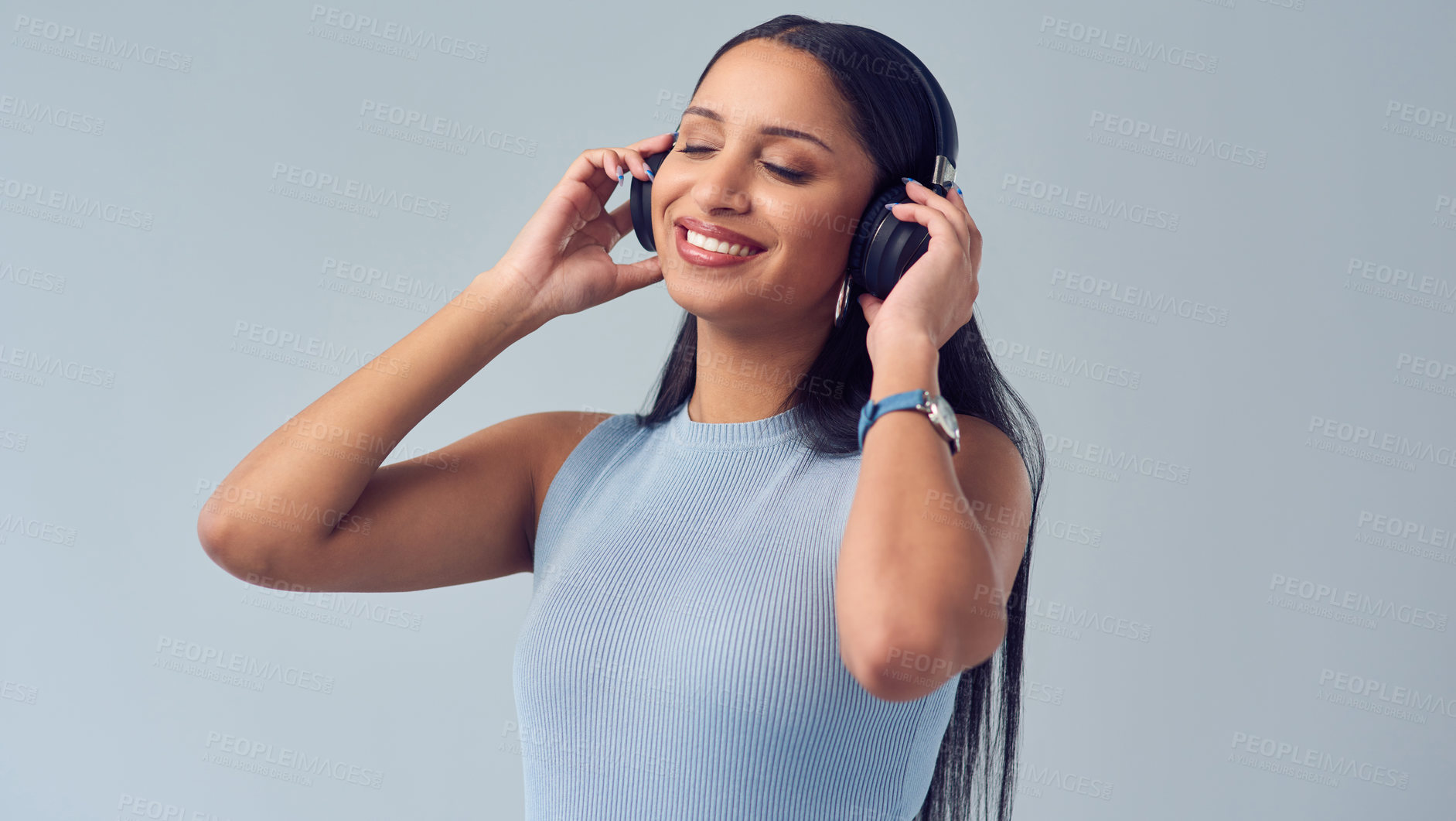 Buy stock photo Cropped shot of an attractive young woman listening to music while standing against a grey background in studio