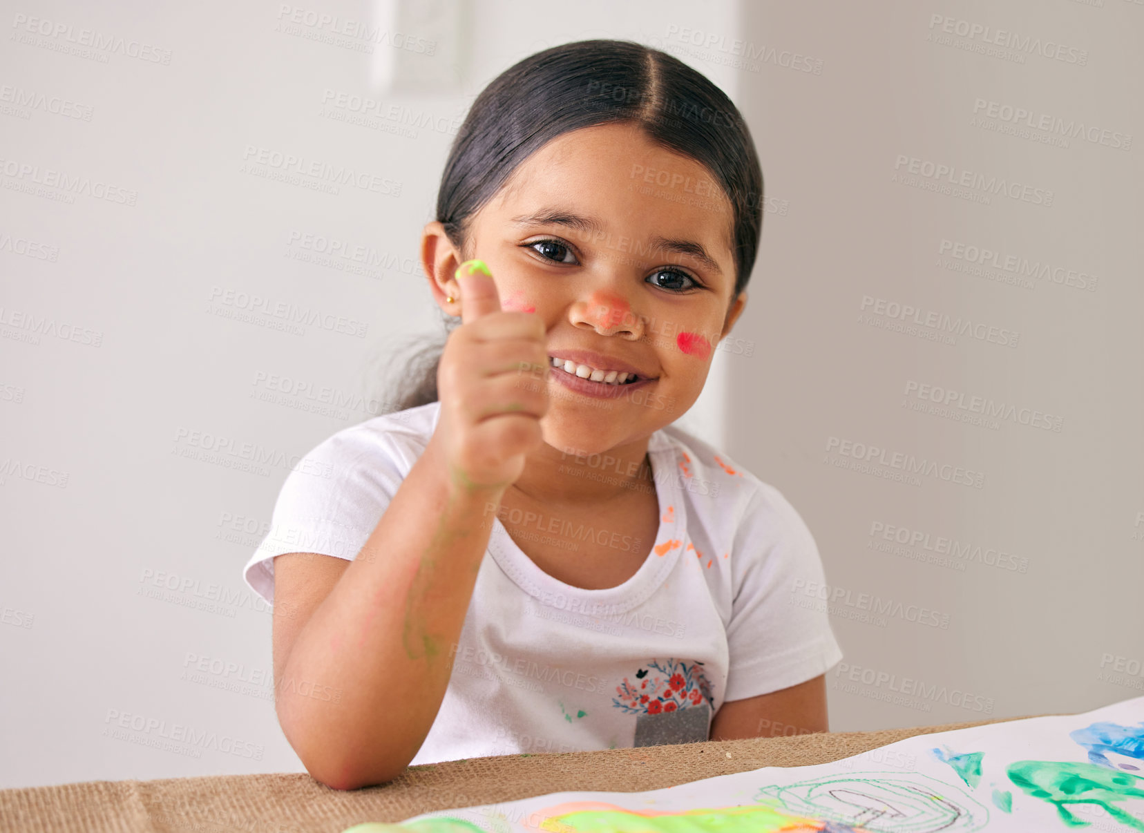 Buy stock photo Shot of an adorable little girl showing thumbs up while painting