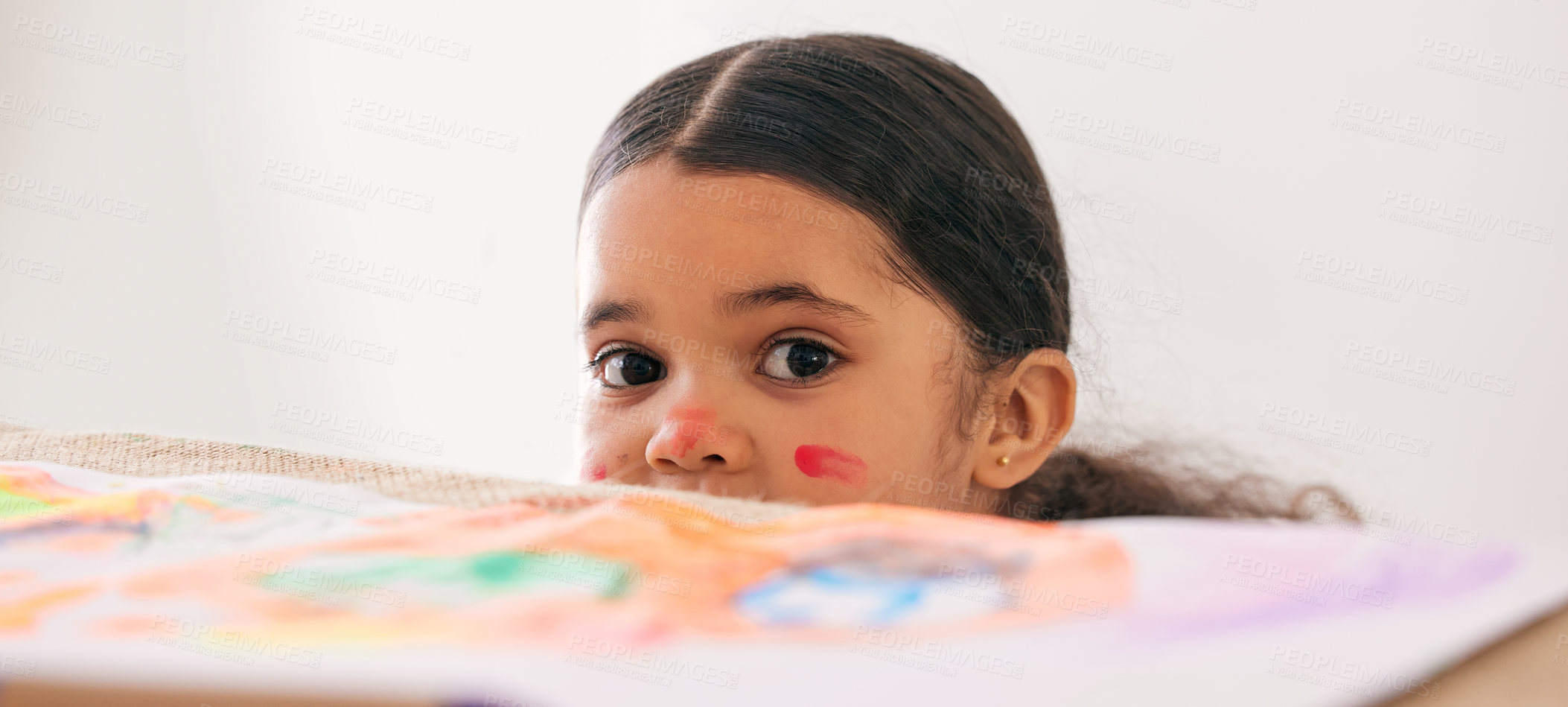 Buy stock photo Shot of an adorable little girl peeking over a table while busy doing art