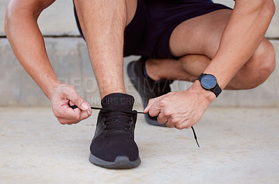 Buy stock photo Cropped shot of an unrecognizable man tying his shoelaces