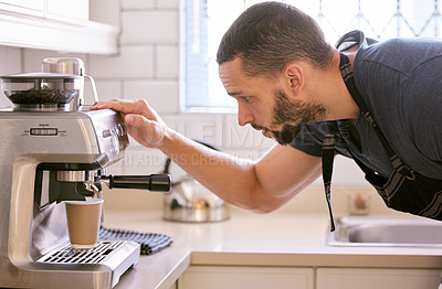Buy stock photo Shot of a young man preparing a cup of coffee