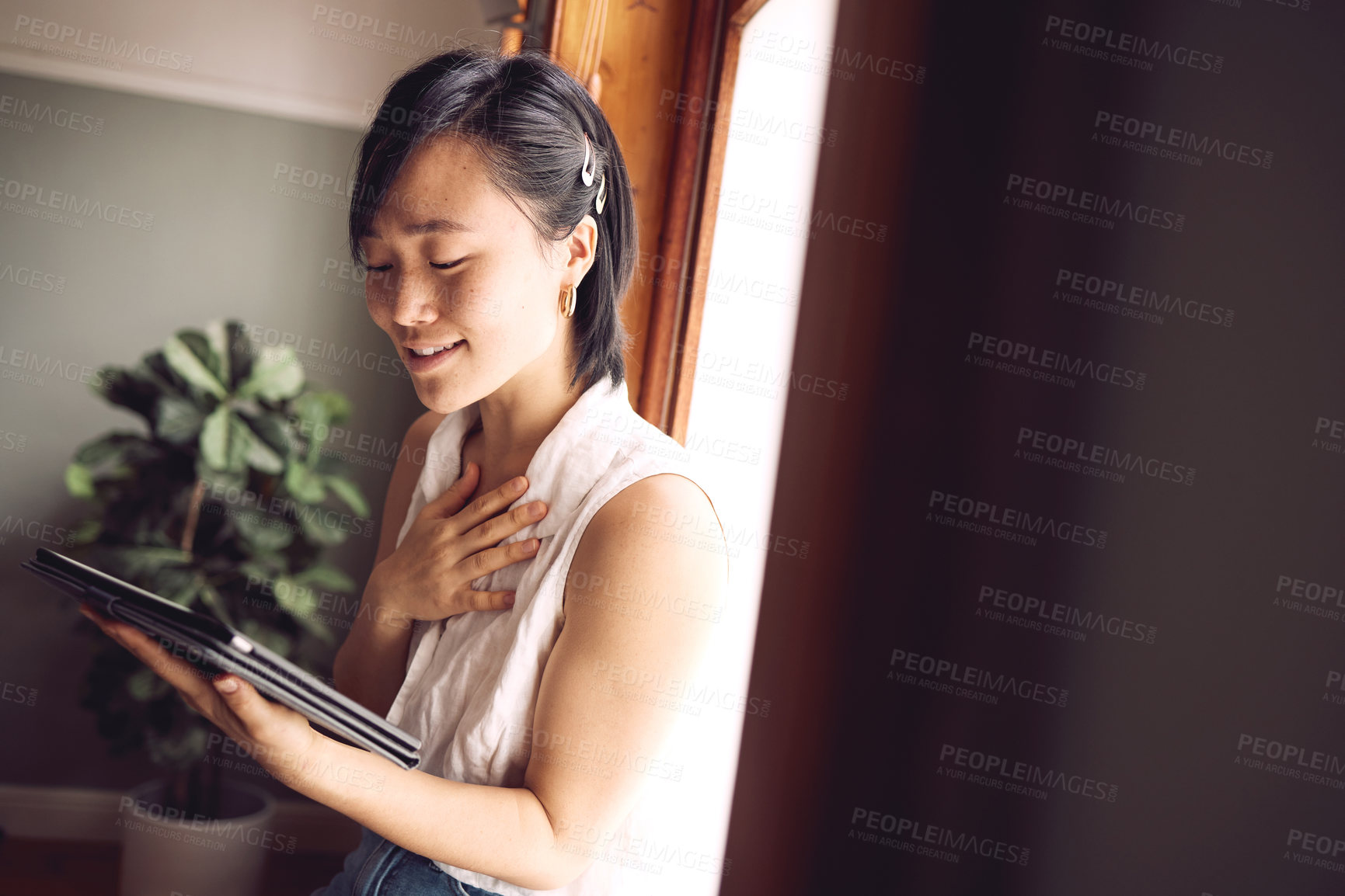 Buy stock photo Shot of a young woman reading her tablet with a happy expression at home