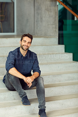 Buy stock photo Cropped portrait of a handsome young businessman sitting alone on a staircase during the day