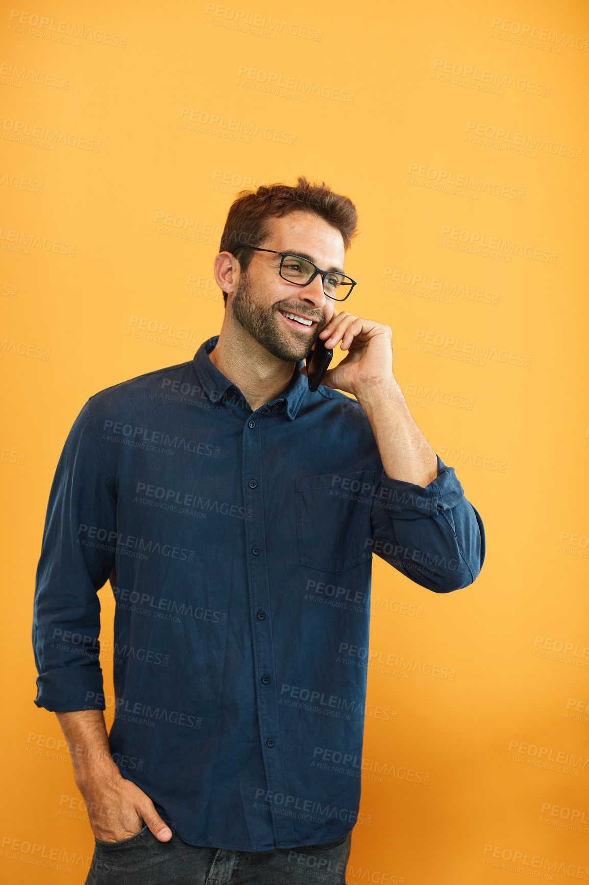 Buy stock photo Cropped shot of a handsome young businessman standing against a yellow studio background and using his cellphone