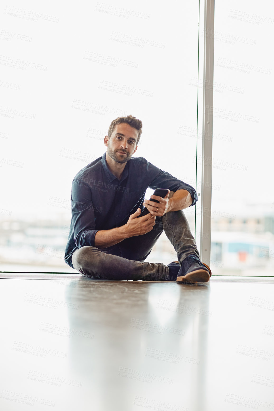 Buy stock photo Full length portrait of a handsome young businessman sitting alone in an airport terminal and using his cellphone