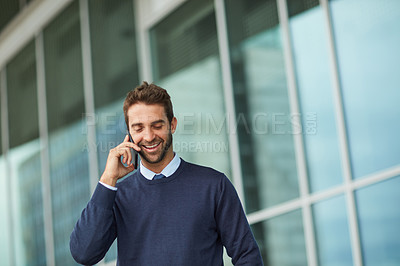 Buy stock photo Cropped shot of a handsome young businessman standing alone outside and using his cellphone during the day