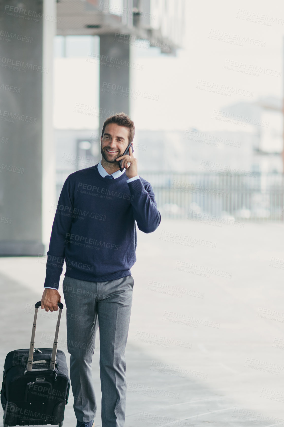 Buy stock photo Cropped shot of a handsome young businessman on the move with a suitcase while using his cellphone during the day