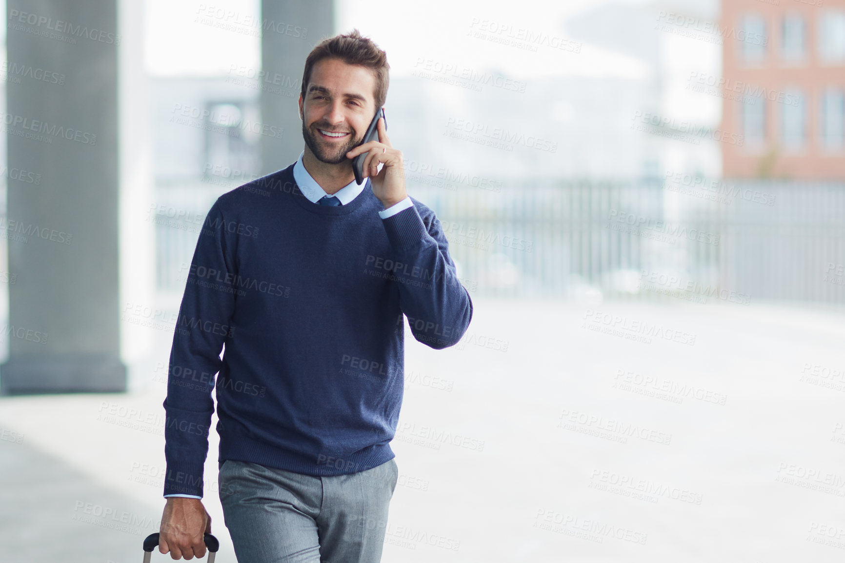 Buy stock photo Cropped shot of a handsome young businessman on the move with a suitcase while using his cellphone during the day