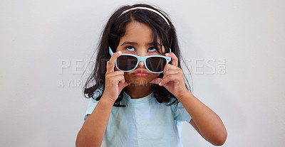 Buy stock photo Girl, child and funny face with sunglasses by wall for summer, holiday and bored at family home. Kid, comic and eyewear for games, fashion and pout with trendy style, growth or development at house