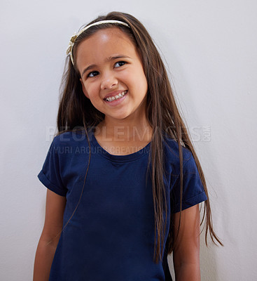 Buy stock photo Thinking, child and smile at a home with casual, youth and cute fashion with idea of a kid. House, relax and adorable girl from Spain with modern style by a white wall with confidence and long hair