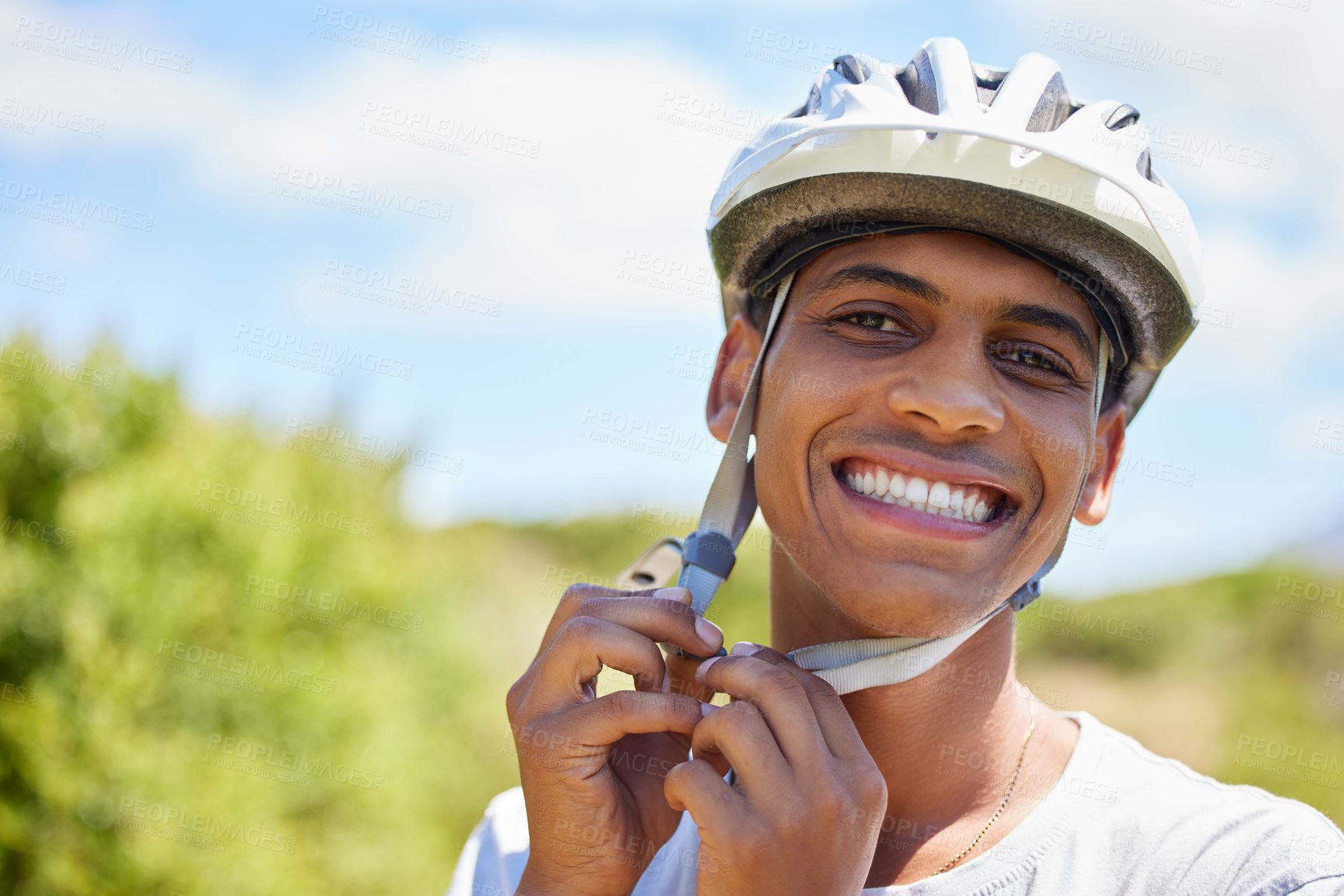 Buy stock photo Shot of a young man tying his helmet in the outdoors