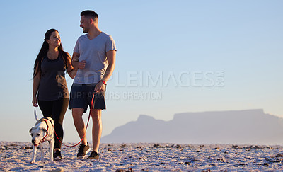Buy stock photo Shot of a couple out for walk at the beach with their dog