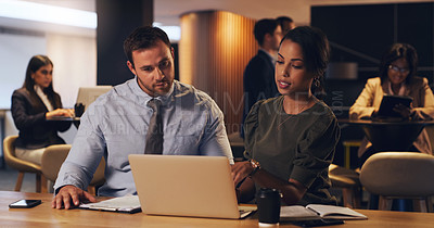 Buy stock photo Shot of two businesspeople working together on a laptop in an office at night