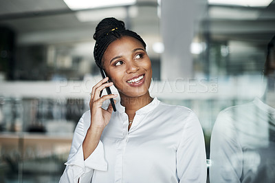 Buy stock photo Shot of an attractive young businesswoman standing alone in the office and using her cellphone during the day