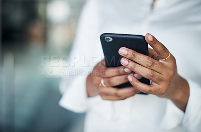 Buy stock photo Cropped shot of an unrecognizable businesswoman standing alone in the office and using her cellphone during the day